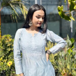 Woman standing outdoors in the sun wearing a silver grey Chanderi dyeable Chikankari style embroidered kurti with matching palazzo pants set