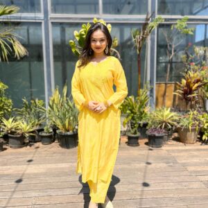 Woman standing outdoors wearing a bright yellow Chanderi dyeable Chikankari style embroidered kurti with matching palazzo pants set